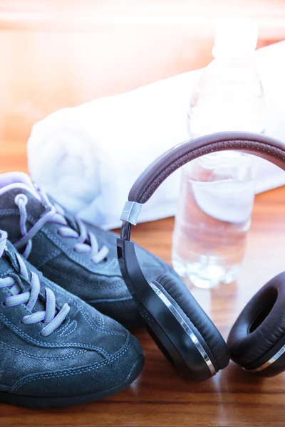 Sport concept.  Healthy lifestyle. Grey sport  shoes and headphones for jogging and sports. Sports equipment.  A water bottle and the white towel on the wooden desk