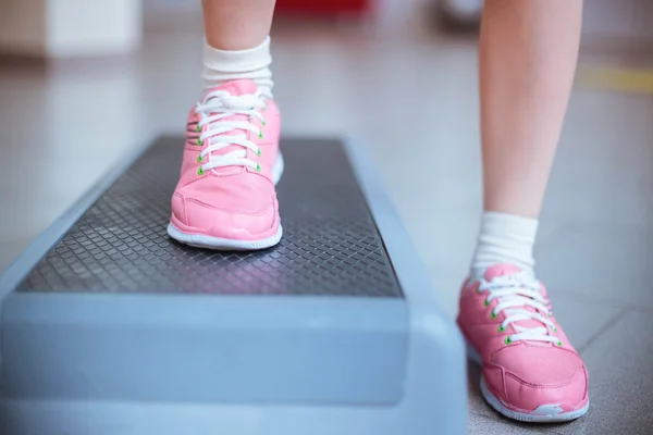 Healthy lifestyle. slender legs of the young girl in a pink sports shoes on a step platform