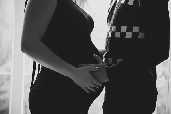 A pregnant woman and her man . Black-and- white photograph. Man holds dearly for his pregnant wife\'s belly