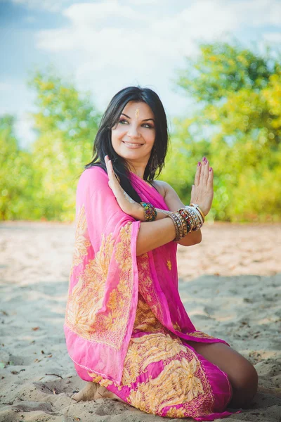 Beautiful caucasian brunette woman in dress in oriental style with oriental patterns on her hands and face, with bracelets in oriental style. Indian woman