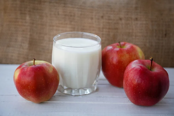 Healthy lifestyle. Useful vitamins food. Proper nutrition. Fruit plate. Apple yogurt diet. Red ripe apples and a cup of yogurt on a wooden table on a light brown background