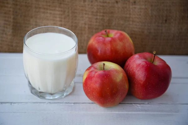 Healthy lifestyle. Useful vitamins food. Proper nutrition. Fruit plate. Apple yogurt diet. Red ripe apples and a cup of yogurt on a wooden table on a light brown background