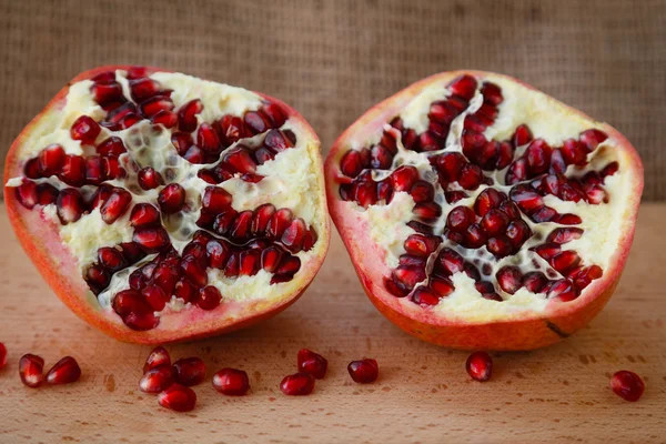 Healthy lifestyle.  Healthy food. Proper nutrition. Fruit plate. Useful vitamins food. Vegetarian food. Fruit diet. Two halves of a ripe pomegranate on a wooden table on light brown background. cut pomegranate with seeds