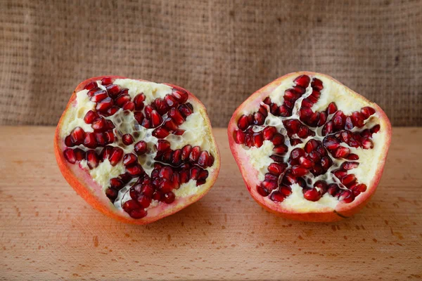 Healthy lifestyle.  Healthy food. Proper nutrition. Fruit plate. Useful vitamins food.  Vegetarian food. Fruit diet. Two halves of a ripe pomegranate on a wooden table on light brown background. cut pomegranate with seeds