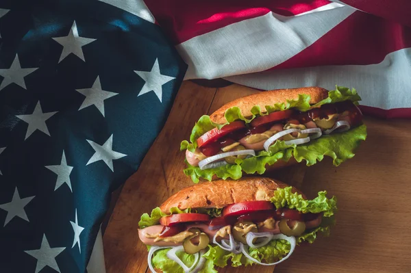 Two fresh hot dogs on a wooden Board, glasses with Cola and American flag