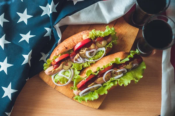 Two fresh hot dogs on a wooden Board, glasses with Cola and American flag