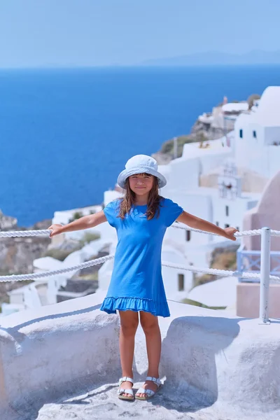Girl dressed in blue dress and hat in the Greek island Santorini