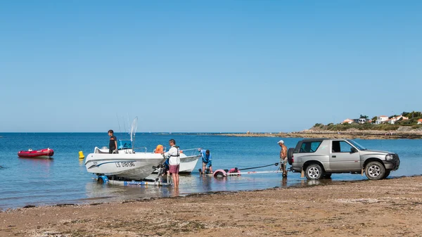 Men getting boats out of water with car on the beach