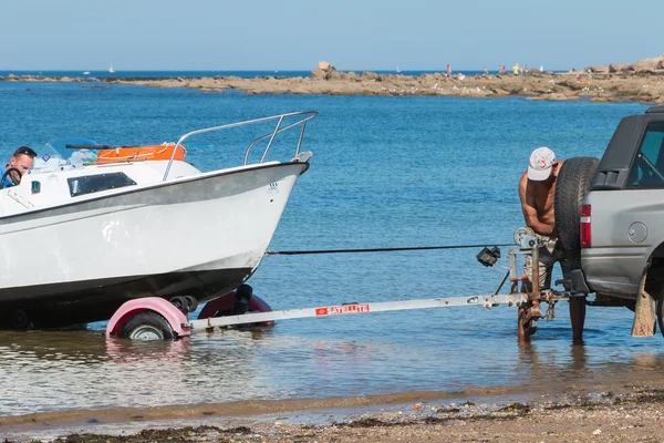 Men getting boats out of water with car on the beach