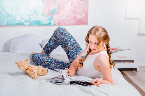 Cute young girl with two braids, at home wearing pajamas, lying