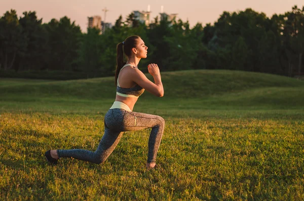 Attractive fitness woman practicing in the park on the grass. It