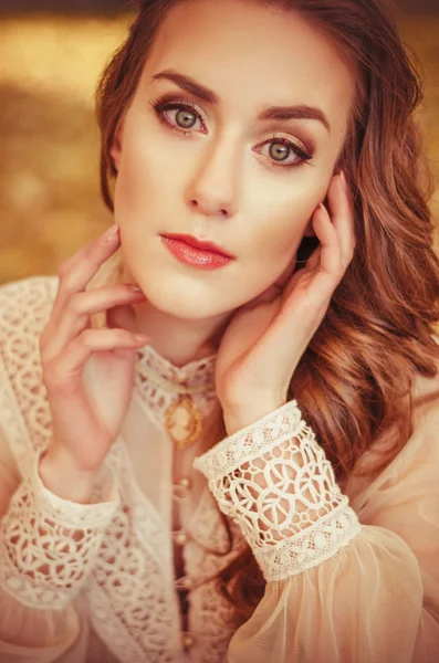 Portrait of a beautiful young girl with blue eyes, a gentle peach dress on a background of autumn leaves