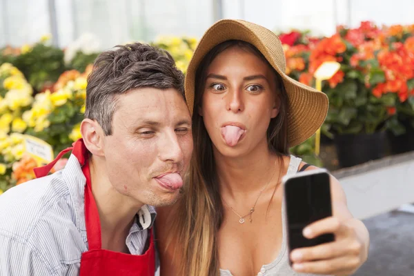 Couple of flower sellers take a funny selfie in greenhouse
