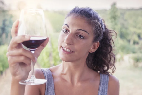 Pretty girl looking glass of wine before drinking