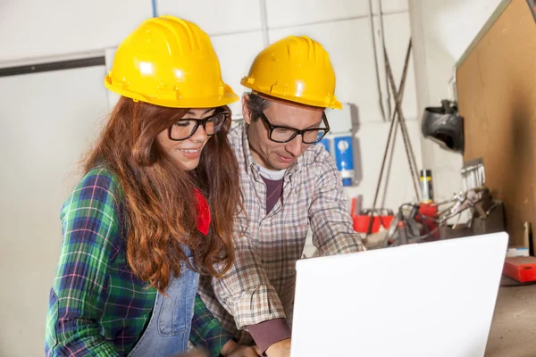 Couple of engineers consult the computer in a steel mill