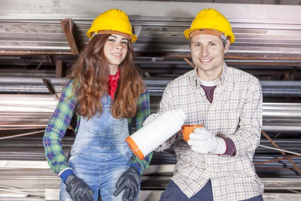 Portrait of young couple of workers on coffee break in a steel m