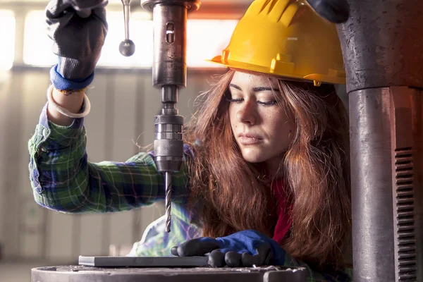 Portrait of pretty girl at work on industrial drilling machine