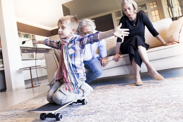 Couple of happy grandparents are fun nephew with skateboard