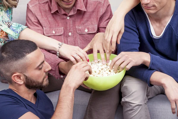 Group of friends eating popcorn on sofa