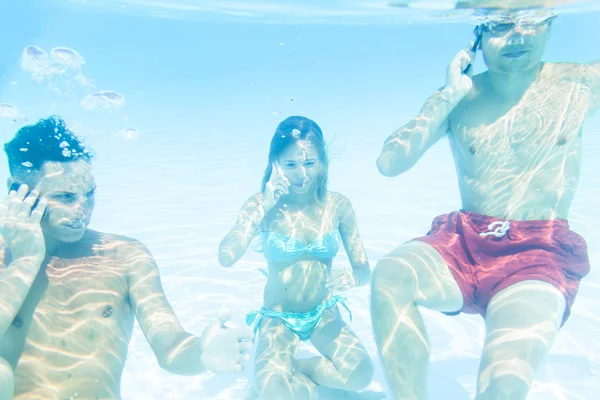 Group of three friends takes a call to smart phone underwater