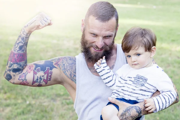 Tattooed father have fun with his son in the park