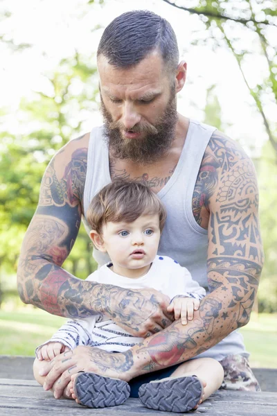 Tattooed father have fun with his son in the park
