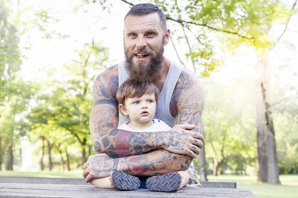 Tattooed father have fun with his son in the park