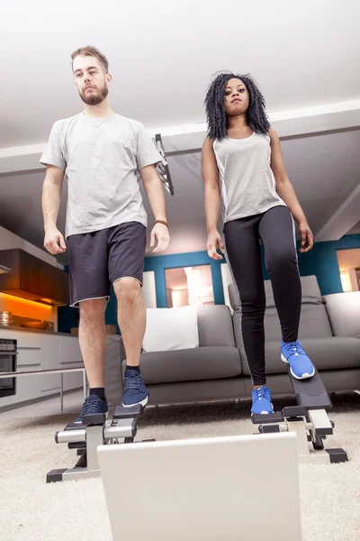 Young couple he trains with the step machine at home