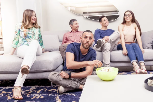 Group of friends watching a football match on tv on the couch