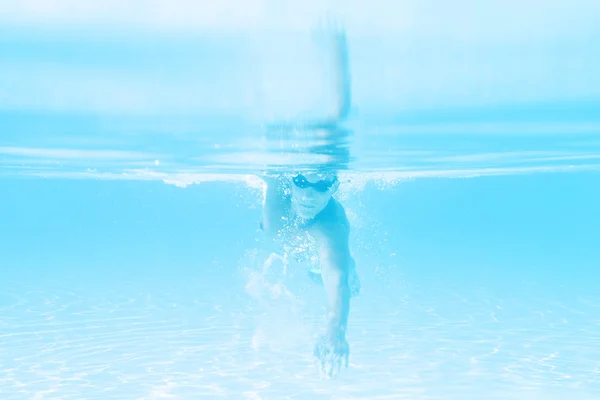 Young man swimming the front crawl style in a pool