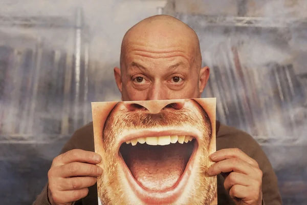 Bald man holding a card with a big smile on it