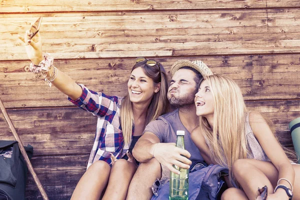 Group of smiling friends taking funny selfie with smart phone