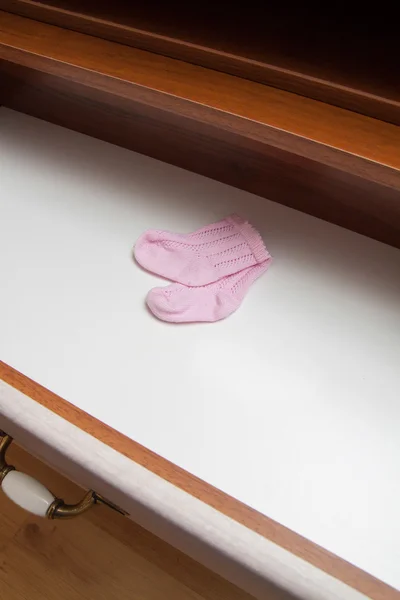 Pink socks in chest of drawers. Expecting for child. Preparation