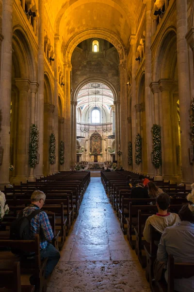 Group of people praying inside the Se Cathedral in Lisbon