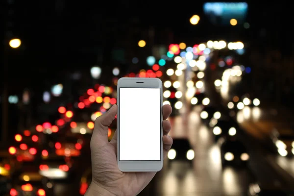 Man holding a smart phone screen blank, blurred traffic jam