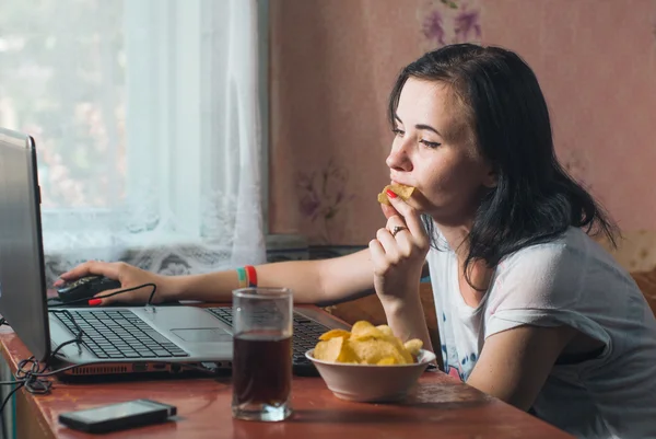 Woman eating chips for laptop, brunette at home,