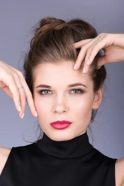 Closeup portrait of beautiful young woman in a black turtleneck. Touches face