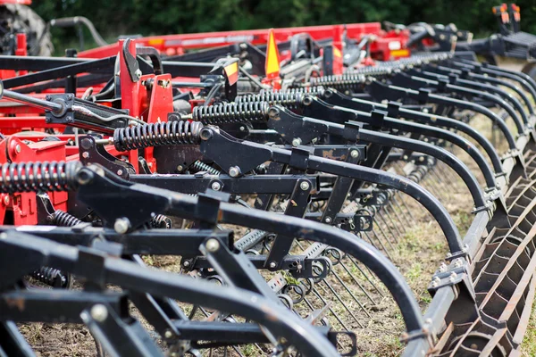 Modern tech red tractor plowing a green agricultural field in spring on the farm. Harvester sowing wheat.