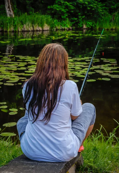 Young woman fishing in pond in summer