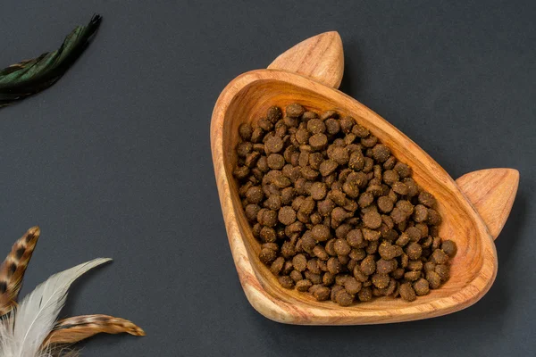 Dry pellet cat food in cat shaped wood bowl