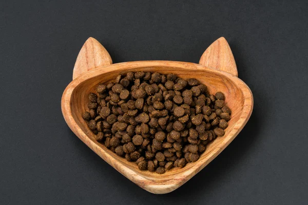 Dry pellet cat food in cat shaped wood bowl
