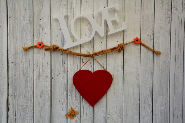 Red heart on white wooden wall with Love Lettering