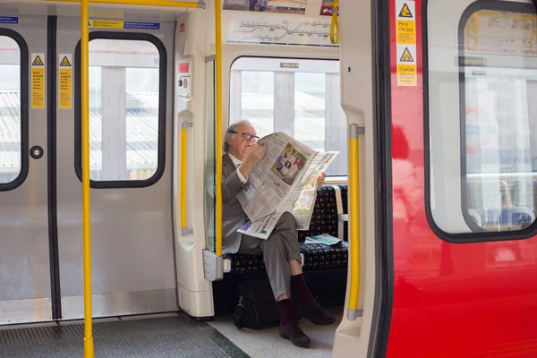 LONDON, UK - April 09, 2015: Senior man reading newspaper in the underground
