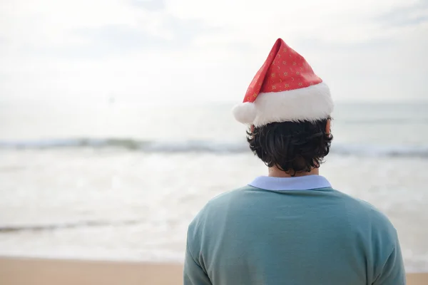 Christmas vacation. Man in santa hat on the beach background.