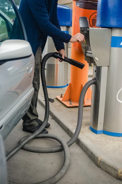 Person paying coins to self service automatic car vacuum machine