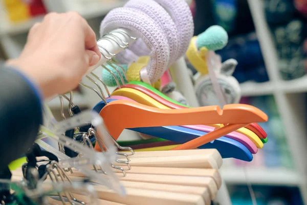 Photo closeup of hand holding colorful hangers hanging on rack