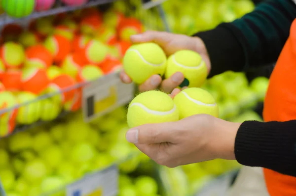 Hand choosing ball for a tennis court on shop background