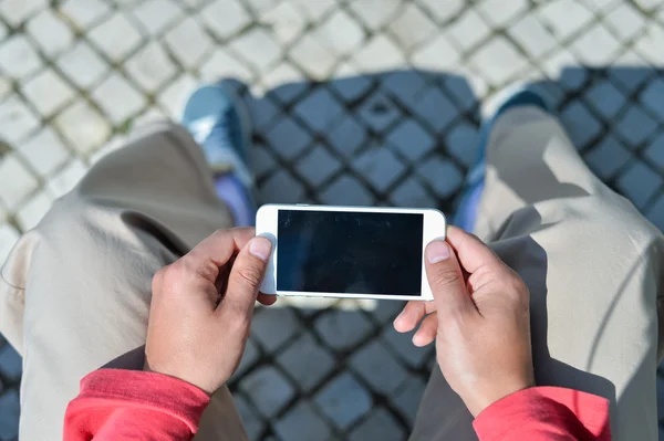 Top view of person sitting on bench hands holding smartphone