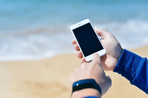 Person holding phone checking connection using smart watch. Sunny background