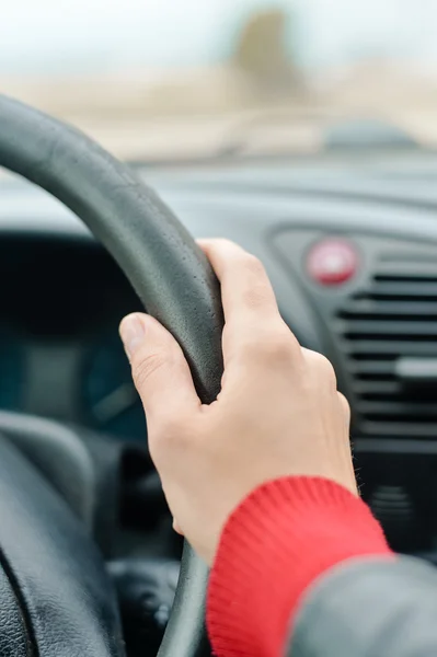 Female hand driver behind the wheel of a car, closeup